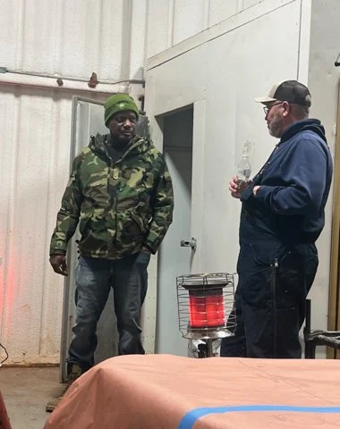 Two veterans and a volunteer standing in front of a barn at a Texas ranch during a hunting trip