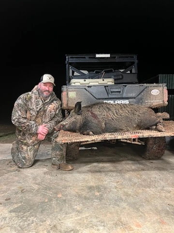 Veteran posing with a hog harvested during a guided hunt